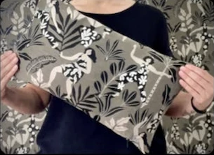 Graues Kissen mit weißen Blüten und Blättern